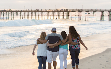 Students hugging in front of the Oceanside Pier